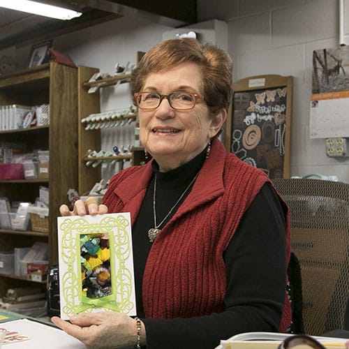 Older Women smiling and holding up a handcrafted greeting card