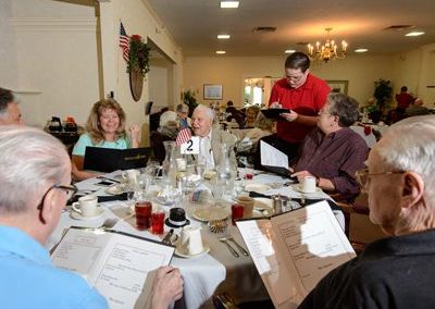 Group of older people sitting around a table with menus ordering food