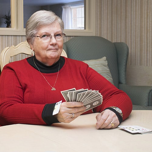 Older Woman holding a deck of cards with an ace up her sleeve