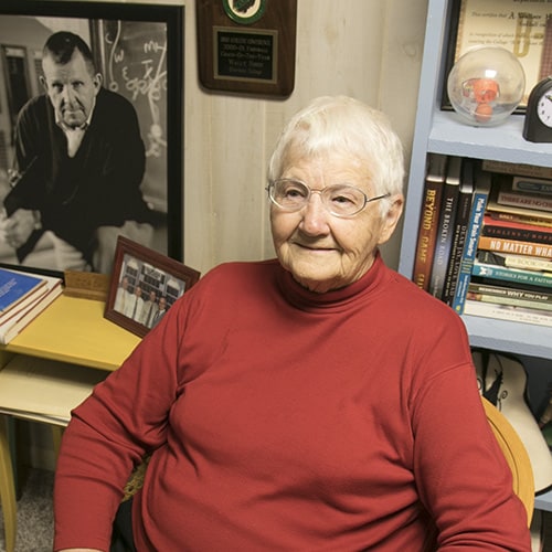 Older Woman smiling with pictures and books behind her