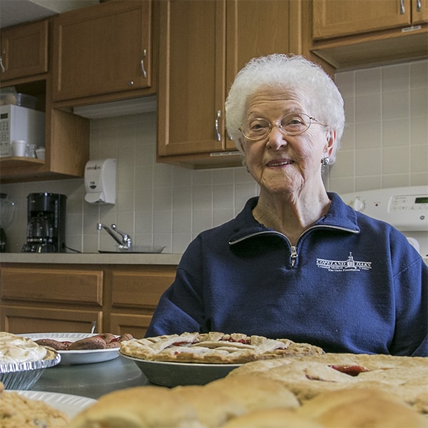 Older Woman smiling with pies in front of her