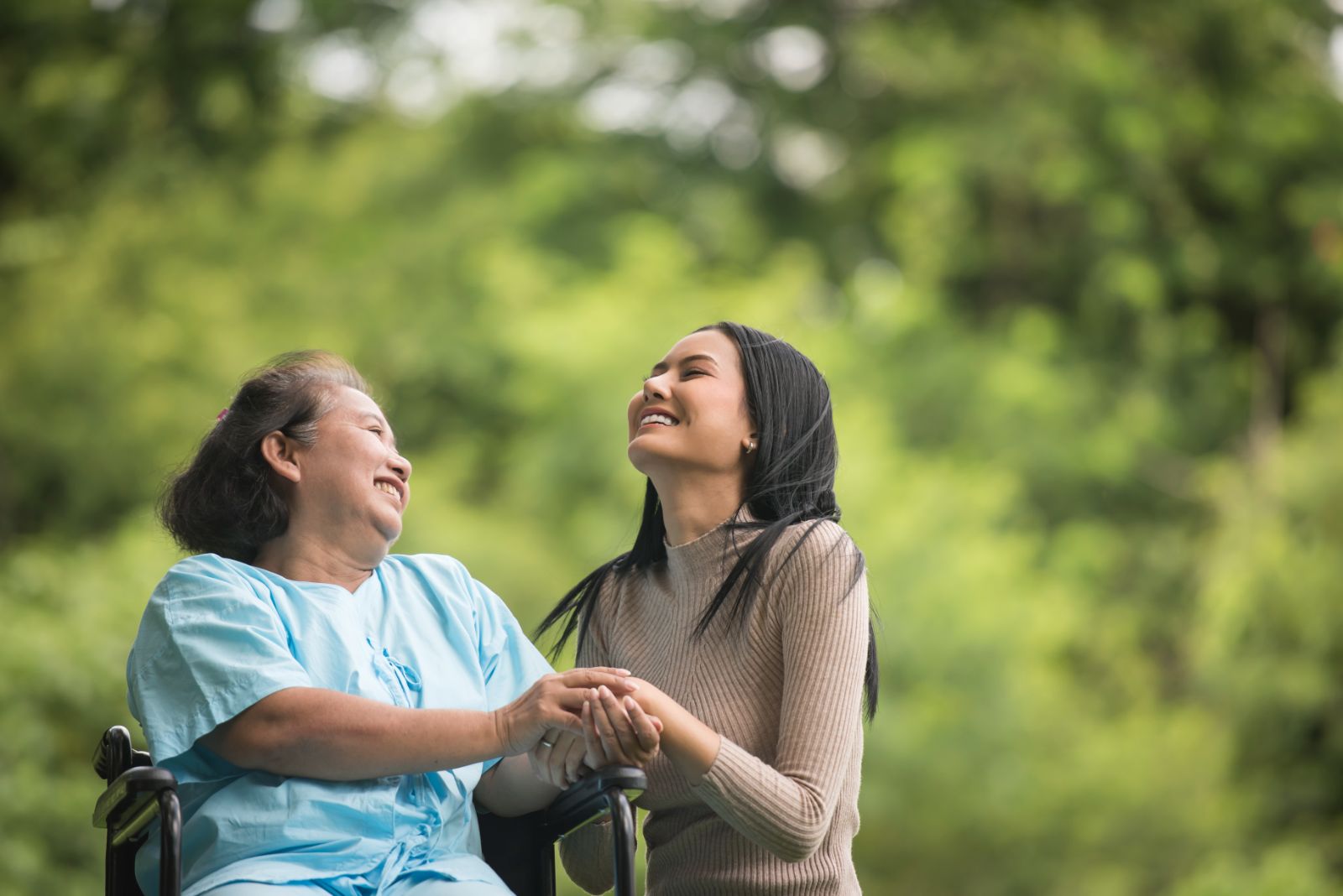 An elderly woman in a wheelchair talking and laughing with her. grandaughter.