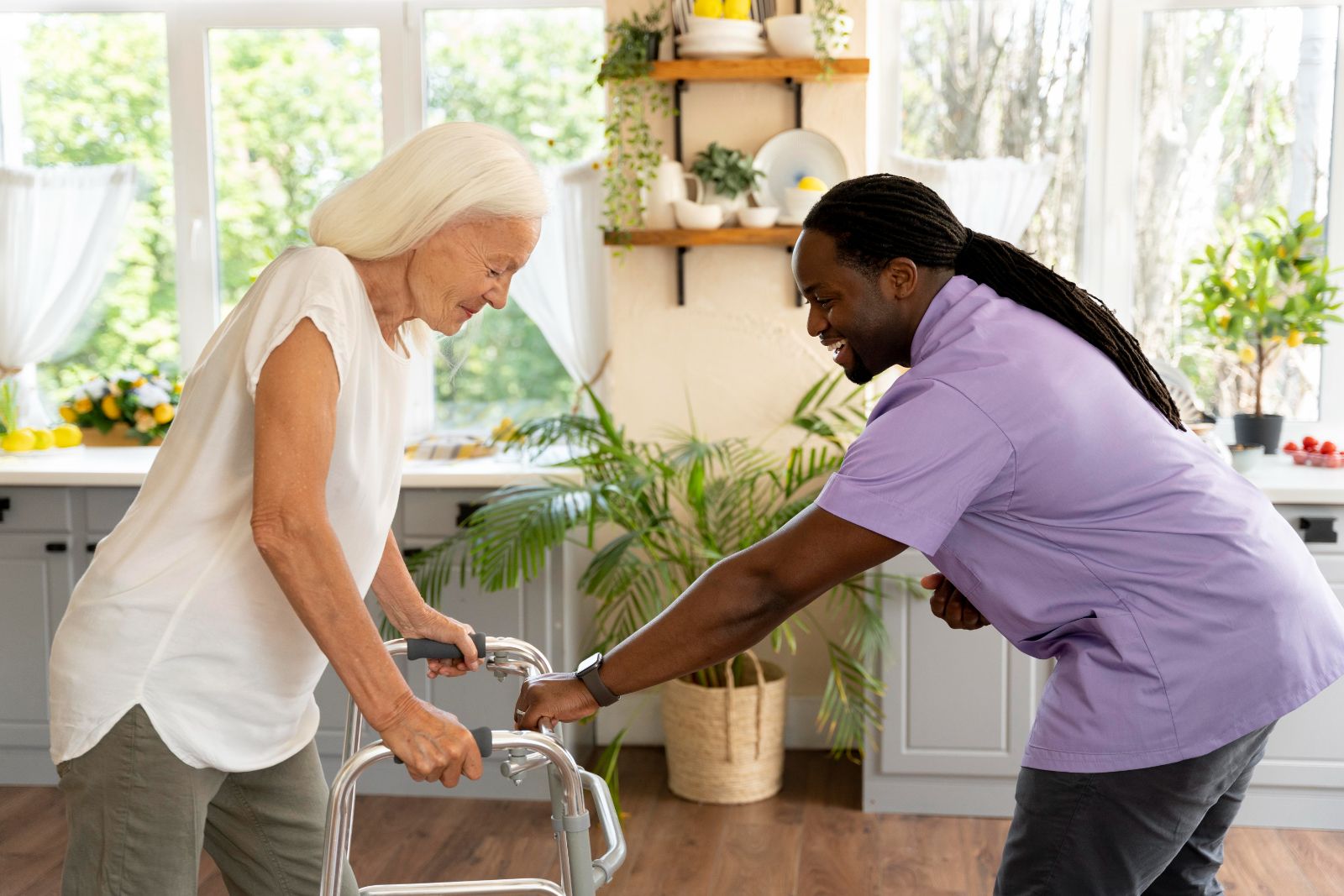 Health care professional aides woman using a walk assist device through a kitchen