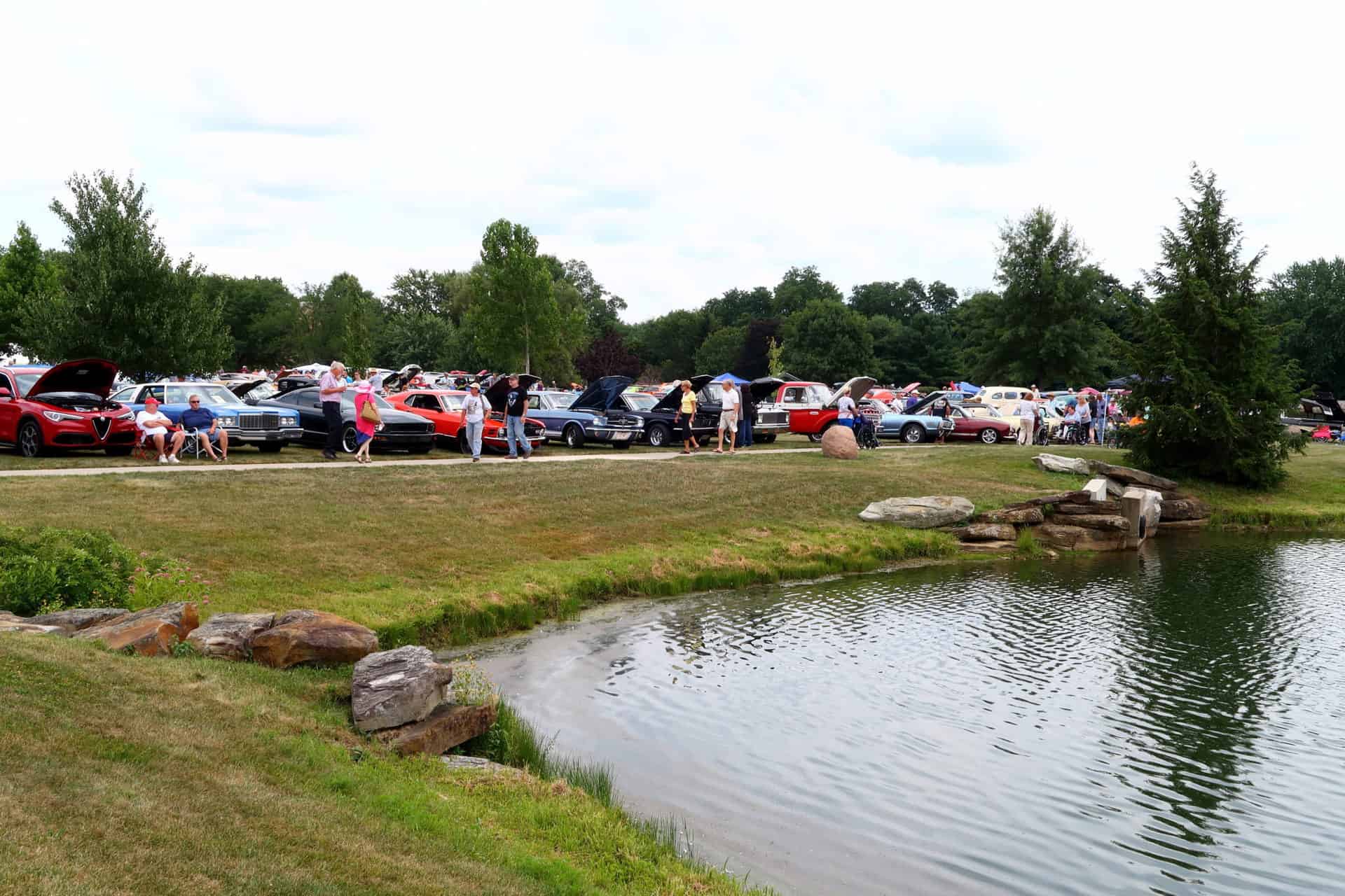 A car show featuring older classic cars in front of the lake at Copeland Oaks