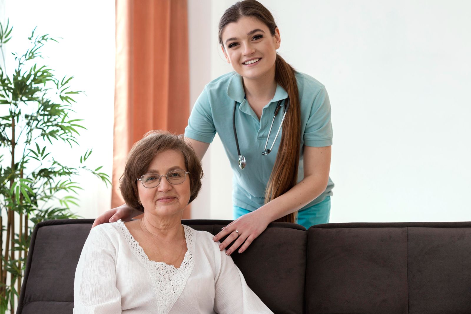A nurse and an older woman smile and pose for a photo.